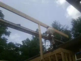 Carpenter setting a ridge beam over a new addition frame — Ice Dam Removal by Roofing Brothers in Forest