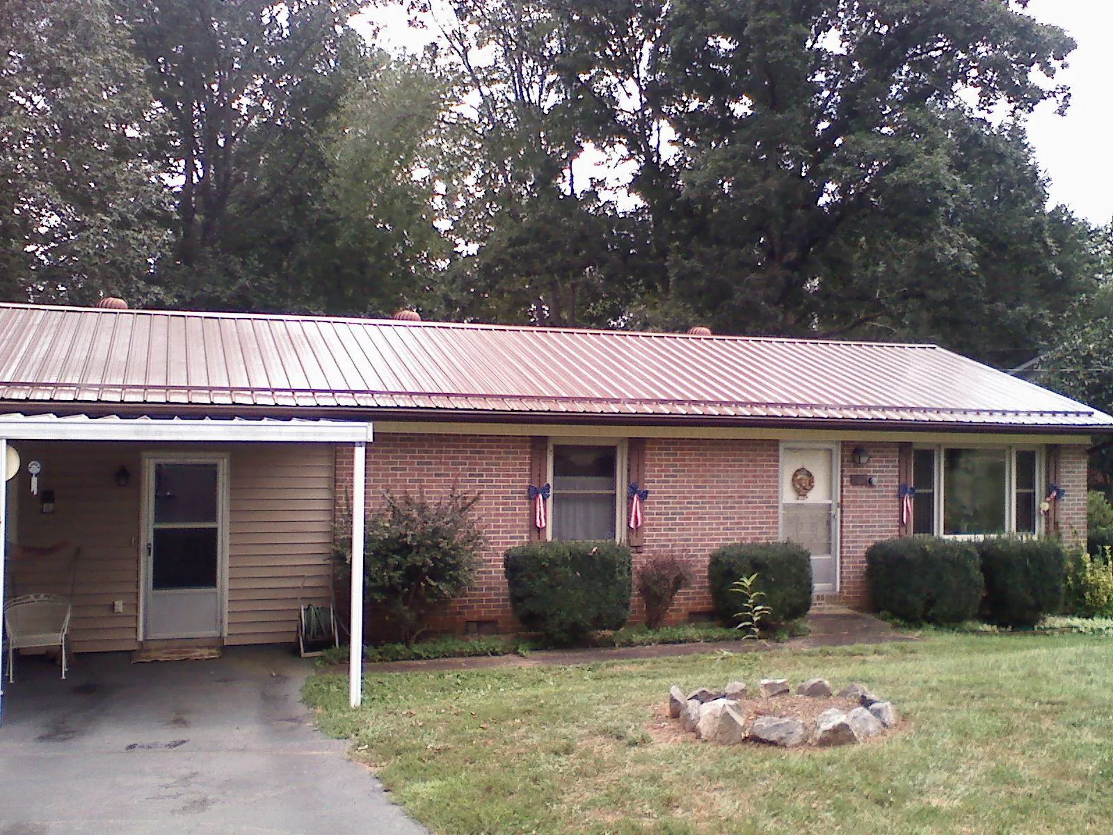 Bronze metal roof and carport on a brick ranch home — Roof Repair work by our crew in Forest